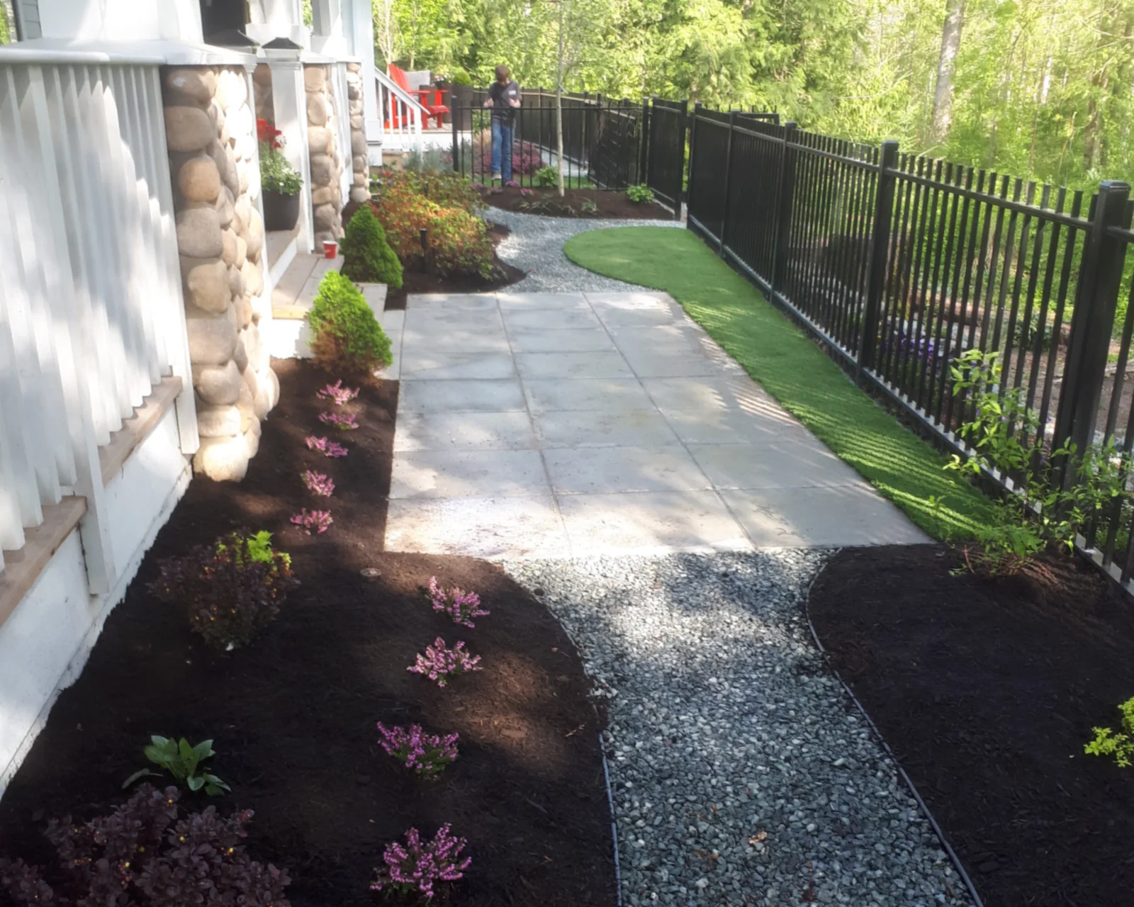 Artificial turf strip beside a paver patio, curving gravel walkway and new mulched garden beds in a Chilliwack yard