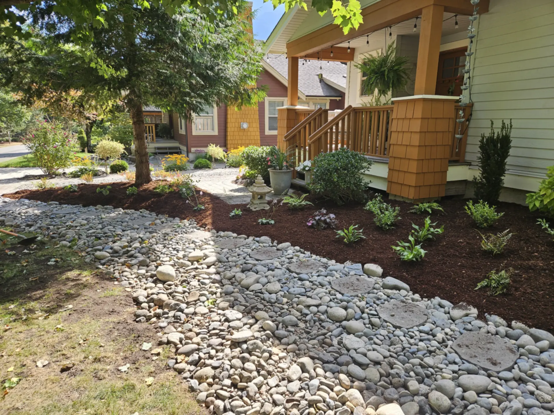 River rock dry creek bed and stepping-stone path in new plantings — landscape design and installation by Blades Landscaping