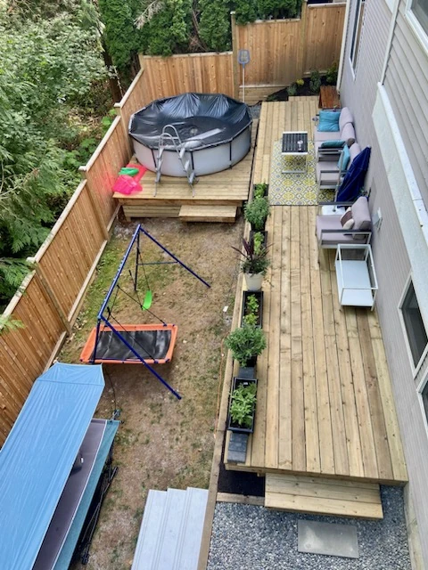 Backyard deck seen from above in Chilliwack, with chairs and planters along its edge and a lower deck with a covered pool