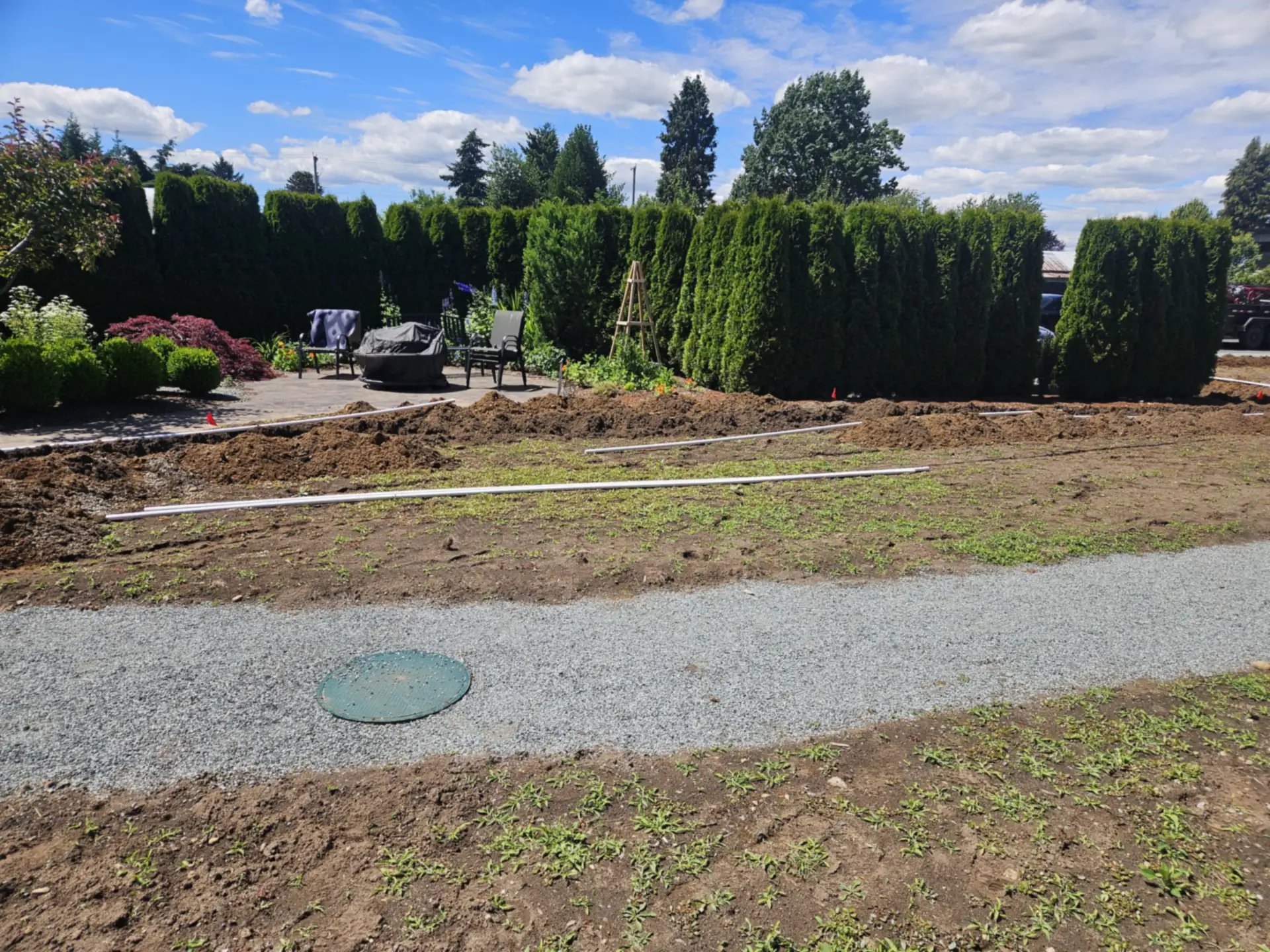 New sprinkler system going in: irrigation pipe laid out across a prepared yard, and a sprinkler head being connected
